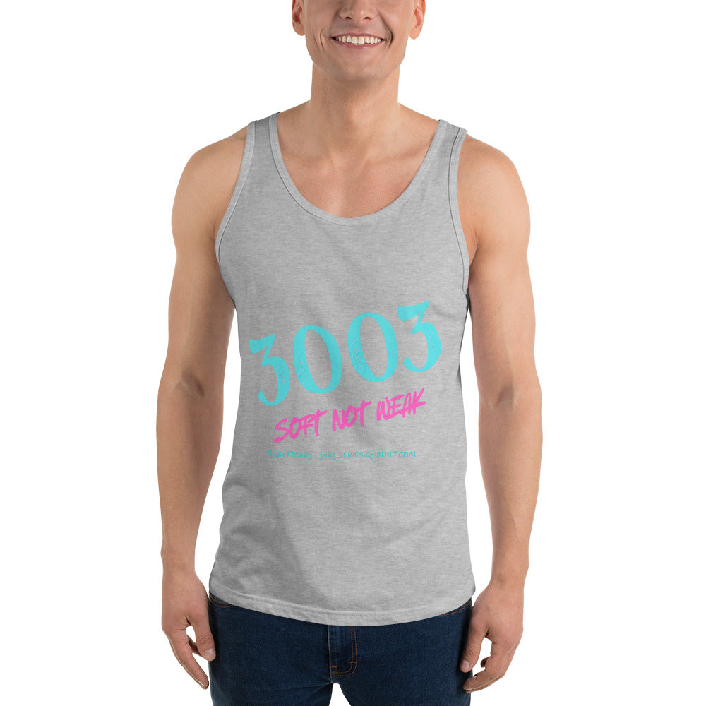 A man wearing a heather gray tank top with a graphic print that reads '3003' in light blue and 'SOFT NOT WEAK' in pink, paired with dark blue jeans.