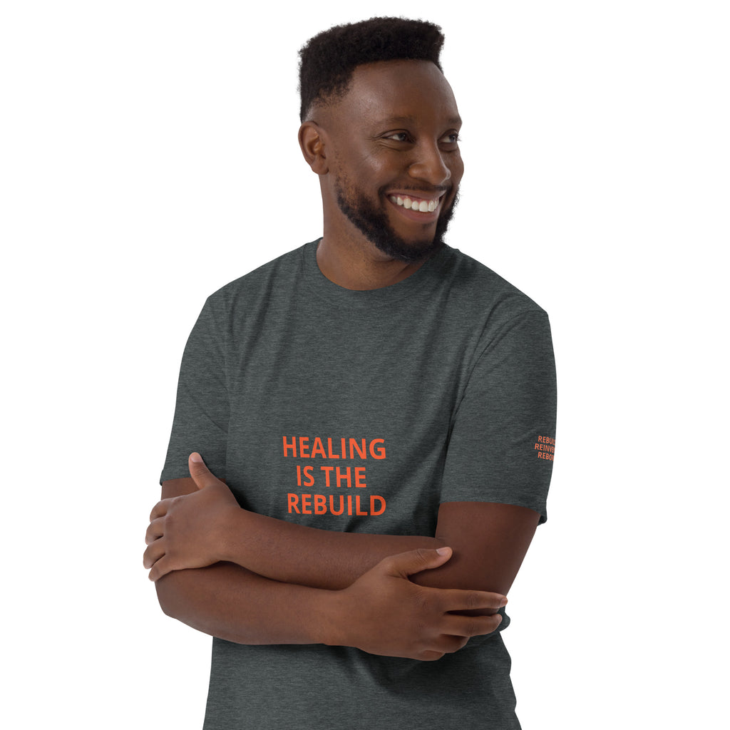 HEALING IS THE REBUILD Dark Heather t-shirt sleeve: REBUILD. REINVENT. REBORN. with R3 bolt logo in orange, blue, purple flames.
