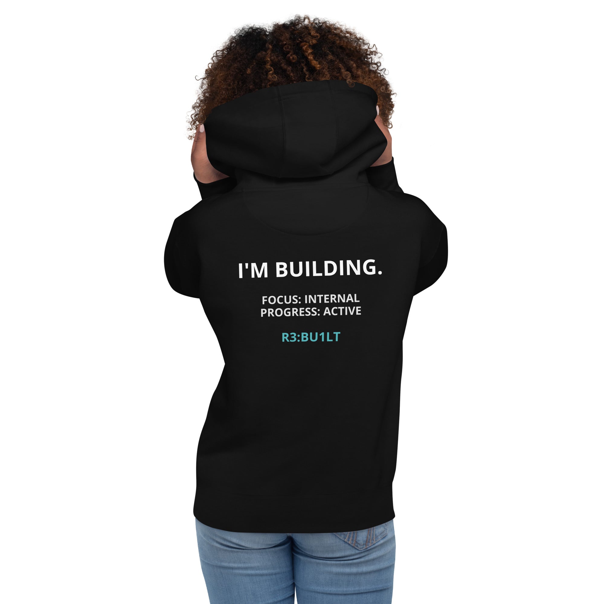 Woman wearing a black hoodie with I'M BUILDING. FOCUS: INTERNAL
PROGRESS: ACTIVE
R3:BU1LT text on the back 