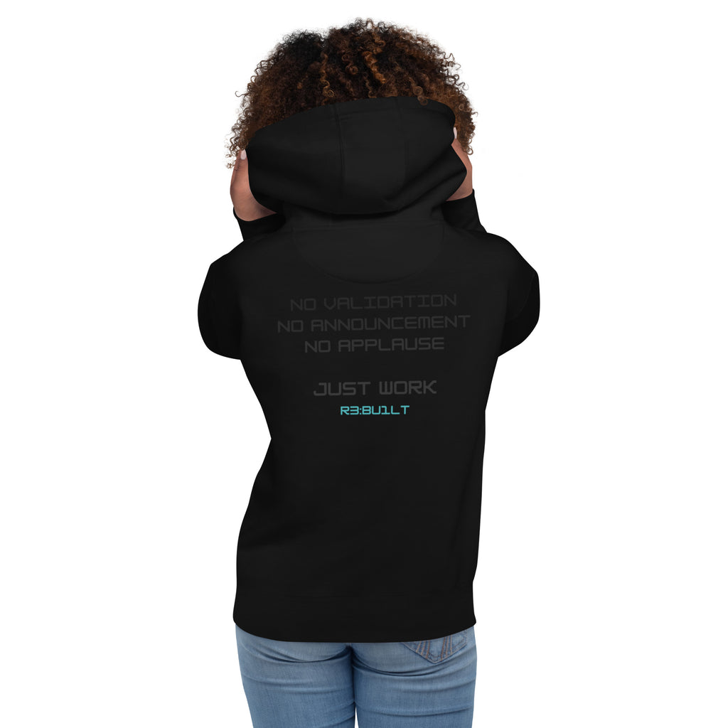Woman wearing a black hoodie with text NO VALIDATION.
NO ANNOUNCEMENT.
NO APPLAUSE.

JUST WORK.
R3:BU1LT on the back.