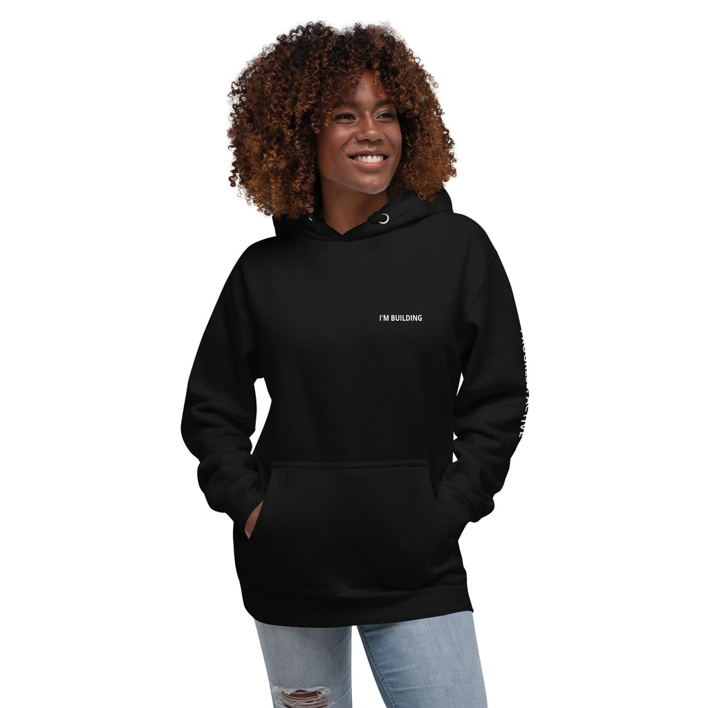 Woman wearing a black hoodie with text on front left chest I'M BUILDING.