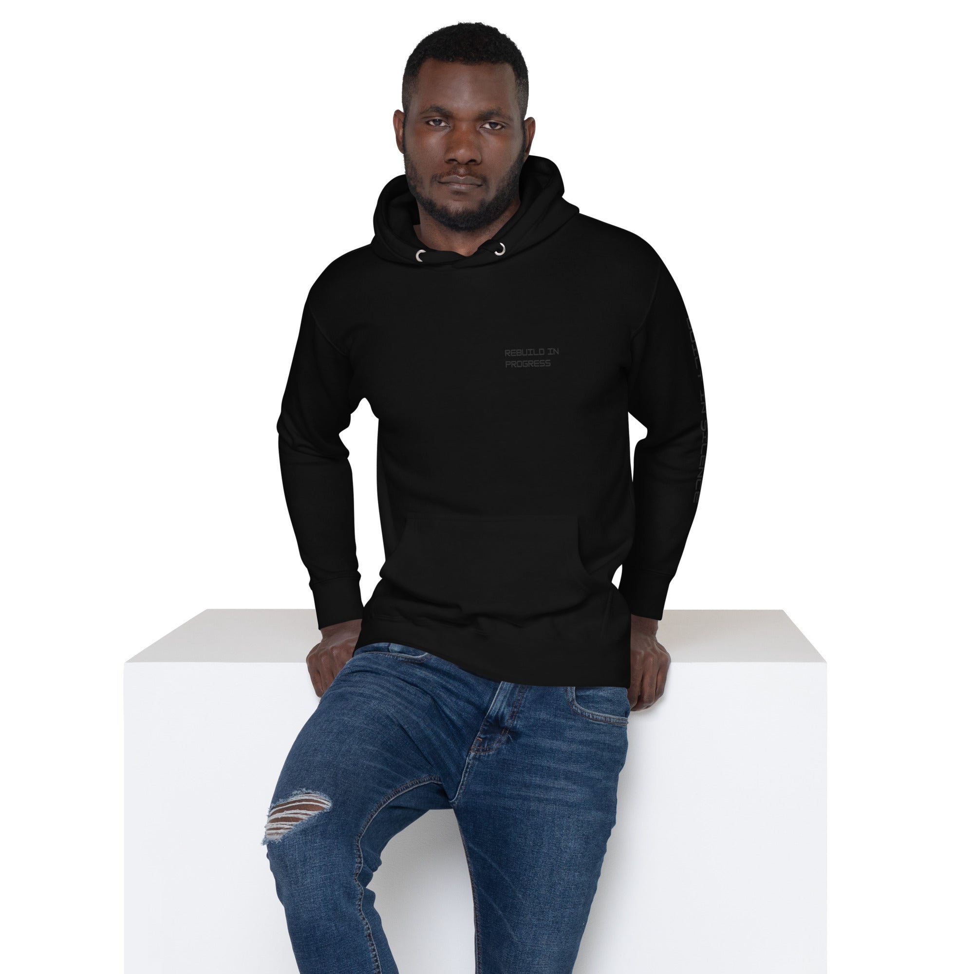 Man wearing a black hoodie with text REBUILD IN PROGRES on front eft chest.