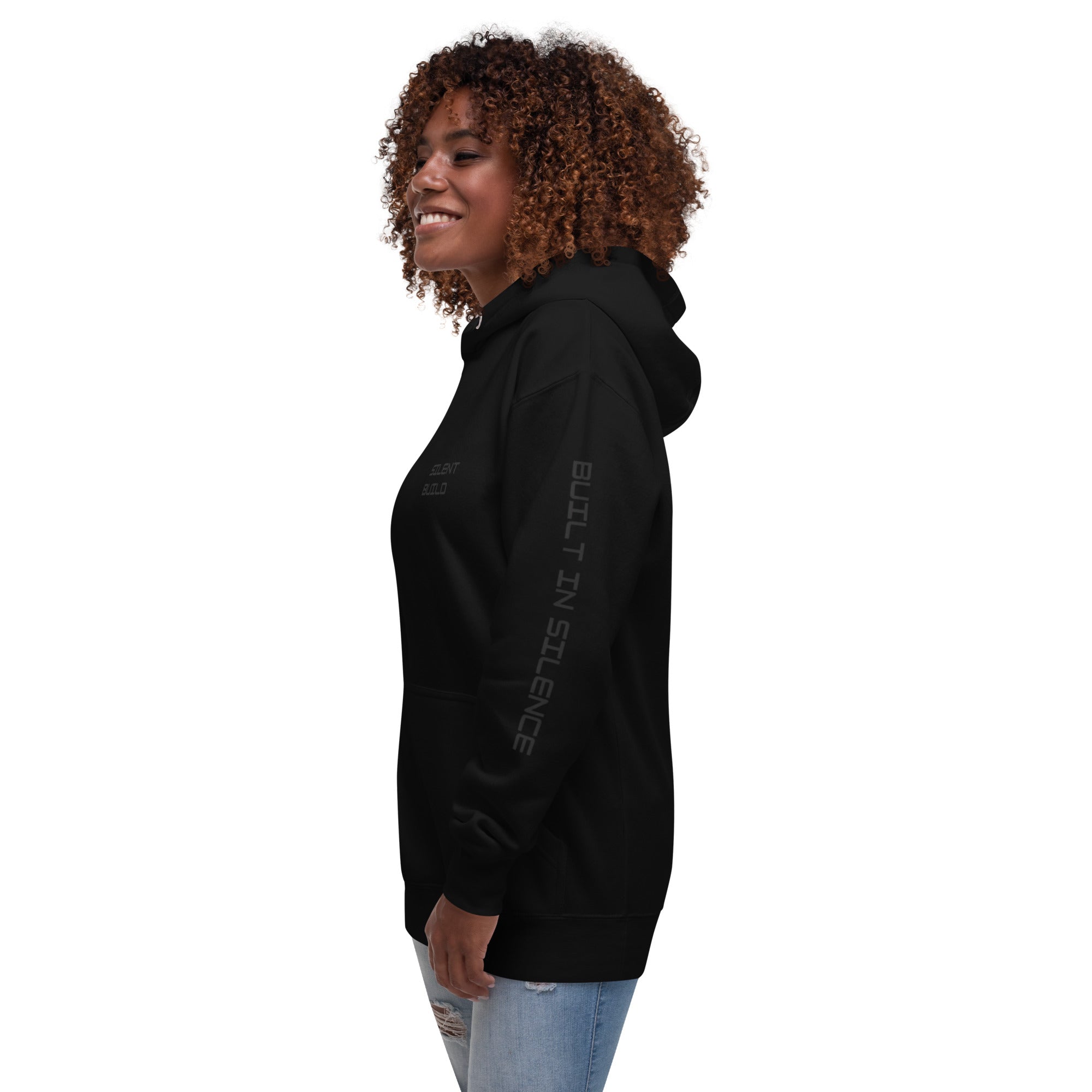 Woman wearing a black hoodie with text BUILT IN SILENCE on the left arm