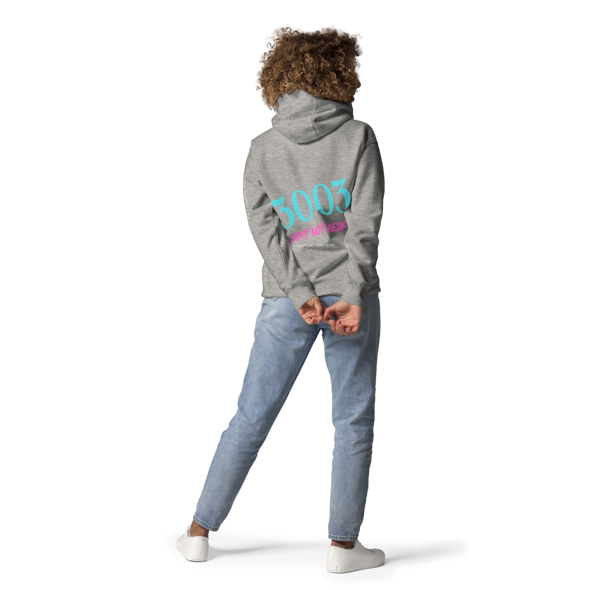 Woman wearing a light gray hoodie with '3003 SOFT NOT WEAK' design on the back.