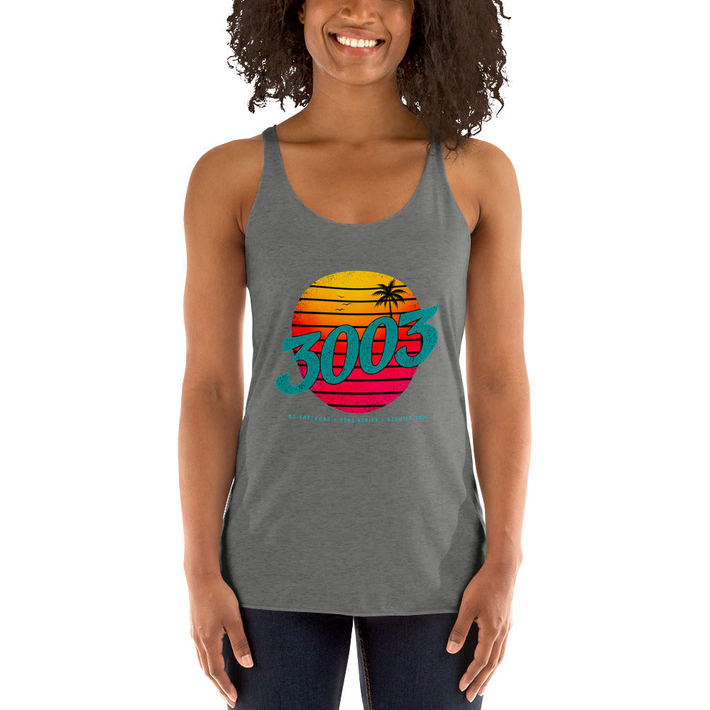 A woman wearing a heather gray racerback tank top with a colorful retro 1980s sunset graphic on the chest featuring the text '3003' and a small palm tree, paired with dark blue jeans.