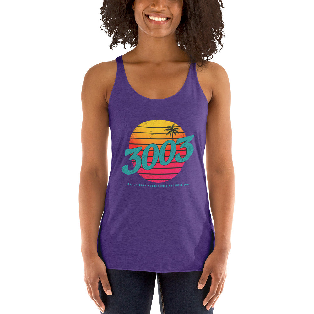 A woman wearing a purple racerback tank top with a colorful retro 1980s-style sunset graphic and the text '3003' on the front, paired with dark jeans.