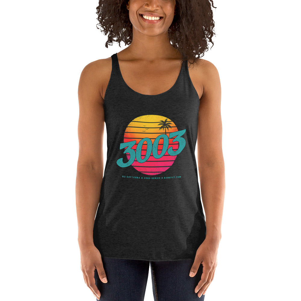 A woman wearing a dark charcoal racerback tank top with a colorful retro 1980s-style sunset graphic and the text '3003' on the front, paired with dark jeans.